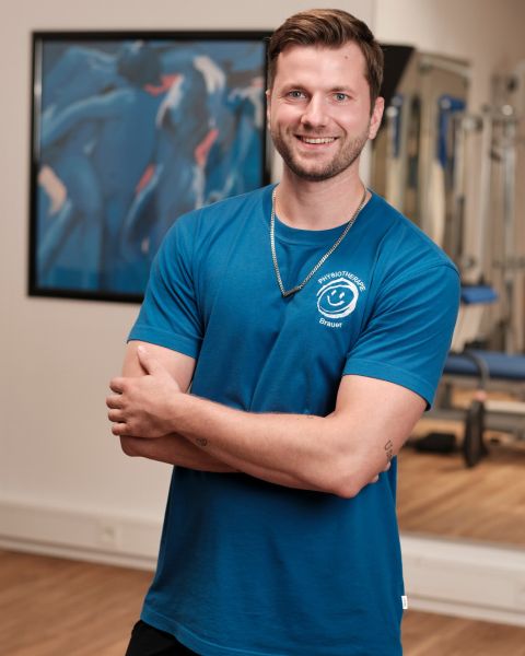 Mittarbeiter mit kurzem braunen Haar, mit blauem Logo T-Shirt