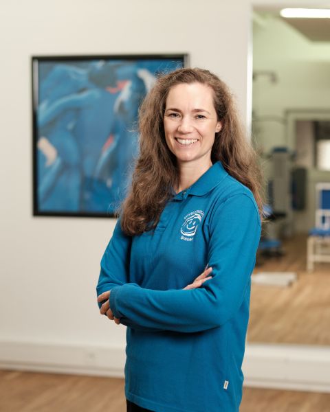 Mitarbeiterin mit braunem langem Haar und blauem Poloshirt