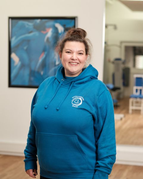Mitarbeiterin mit braunem Bob und blauem Praxis-Pullover